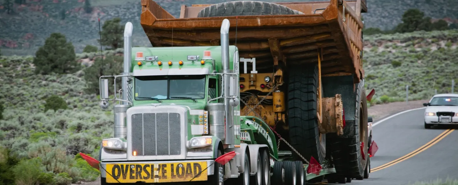 Oversized freight management truck hauling heavy mining equipment on highway